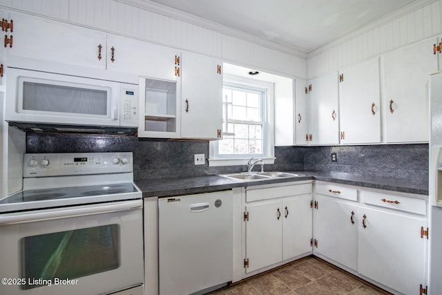 kitchen featuring tasteful backsplash, white appliances, crown molding, dark countertops, and a sink