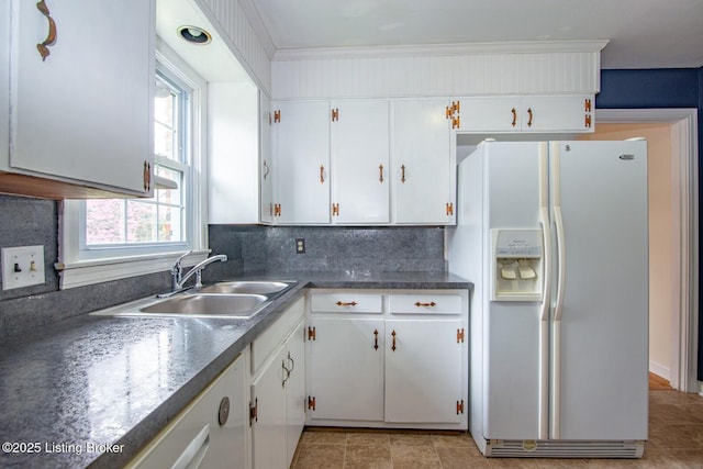 kitchen featuring a sink, white fridge with ice dispenser, white cabinetry, and dark countertops