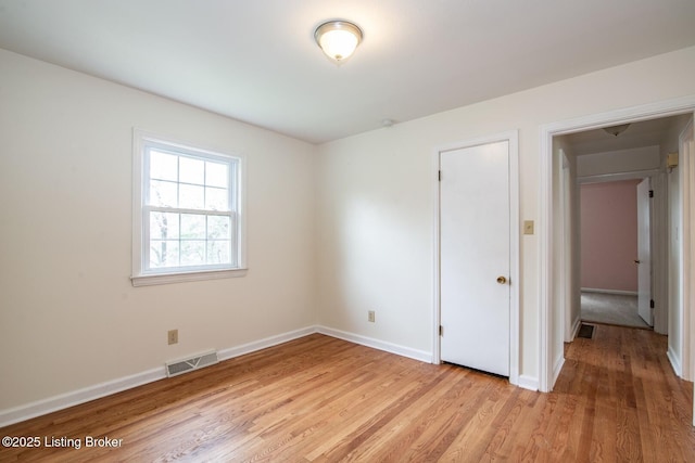 empty room featuring visible vents, baseboards, and light wood-type flooring