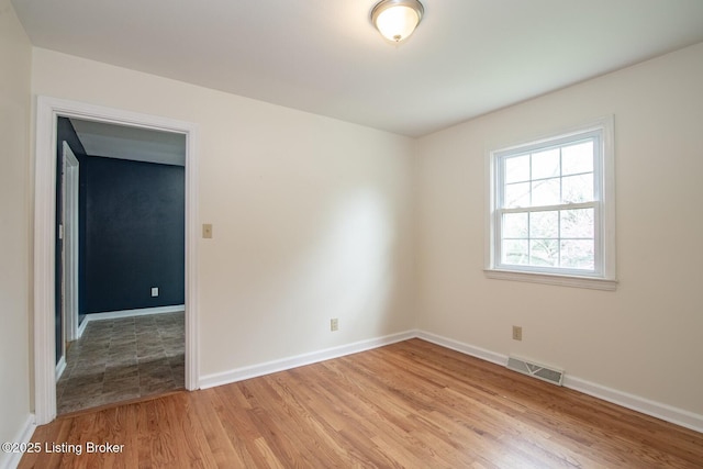 empty room featuring visible vents, baseboards, and light wood-style floors