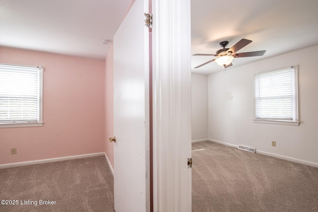 unfurnished room with carpet, visible vents, baseboards, and a ceiling fan