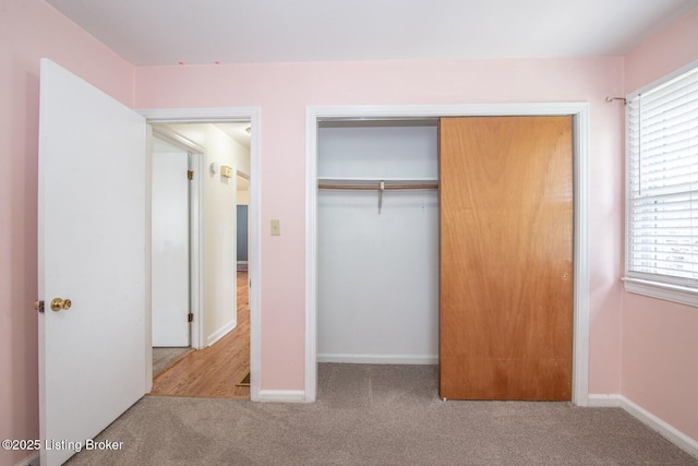 unfurnished bedroom featuring carpet flooring, multiple windows, a closet, and baseboards