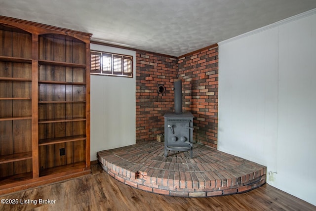 unfurnished living room with wood finished floors, a wood stove, and ornamental molding