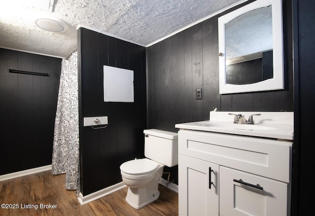bathroom featuring vanity, a textured ceiling, toilet, wood walls, and wood finished floors
