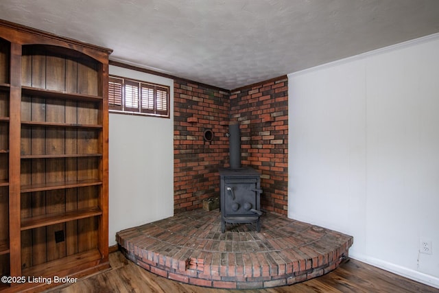 details featuring wood finished floors, a wood stove, baseboards, and ornamental molding