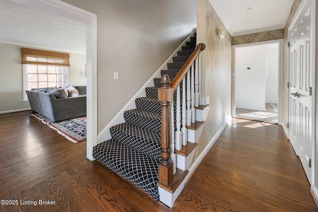 staircase featuring baseboards, crown molding, and wood finished floors