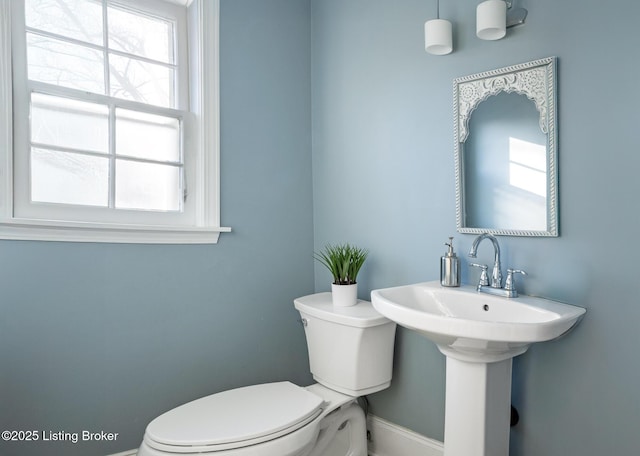 half bath with baseboards and toilet