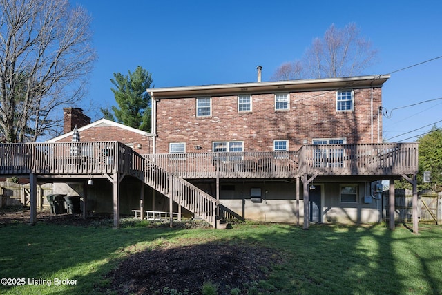 back of property featuring stairway, brick siding, a deck, and a lawn