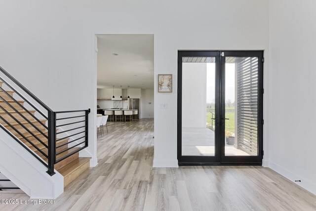 entryway with baseboards, light wood-style flooring, french doors, and stairs