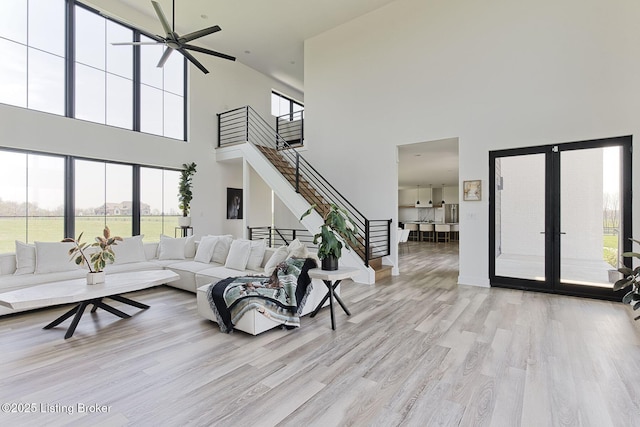 living room with stairway, a high ceiling, plenty of natural light, and french doors
