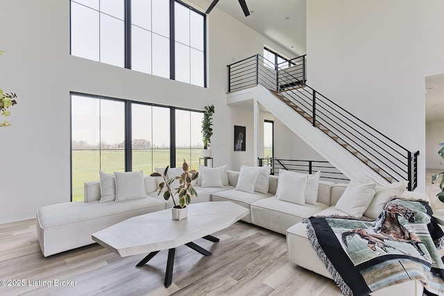 living area with light wood finished floors, a high ceiling, a wealth of natural light, and stairway