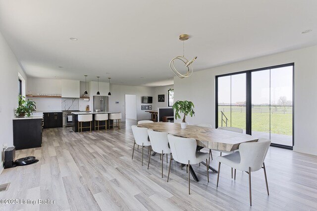 dining area with baseboards, light wood-style floors, and visible vents