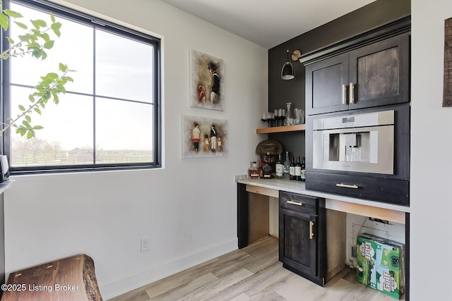 bar featuring a wealth of natural light, light wood finished floors, and baseboards