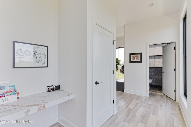 hall featuring light wood-type flooring and baseboards