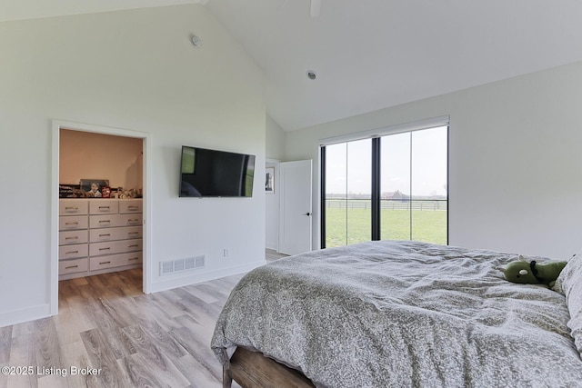 bedroom featuring visible vents, a spacious closet, light wood-style floors, access to outside, and high vaulted ceiling