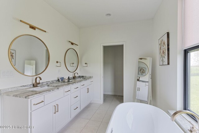 bathroom with a freestanding bath, tile patterned flooring, a sink, and double vanity