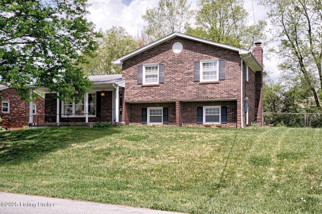 tri-level home with brick siding, fence, a front lawn, and a chimney