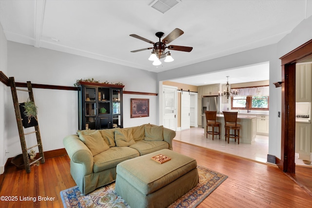 205 Birch Ave, La Grange, KY 40031 - living room with a barn door, light wood-style floors, visible vents, baseboards, and ceiling fan with notable chandelier