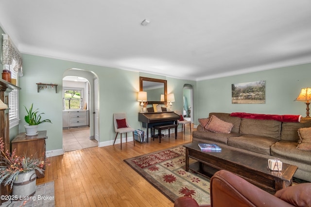 living area featuring arched walkways, light wood-style floors, and baseboards