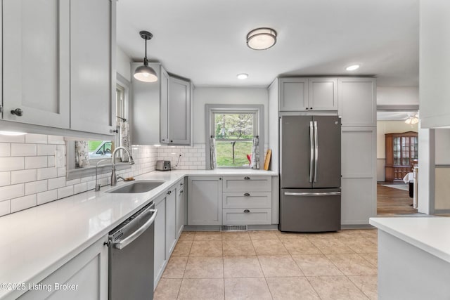 kitchen featuring backsplash, appliances with stainless steel finishes, gray cabinets, and a sink