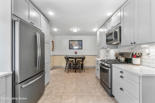 kitchen with tasteful backsplash, baseboards, recessed lighting, light countertops, and appliances with stainless steel finishes