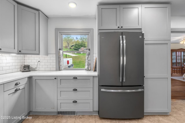 kitchen with gray cabinets, light countertops, and freestanding refrigerator