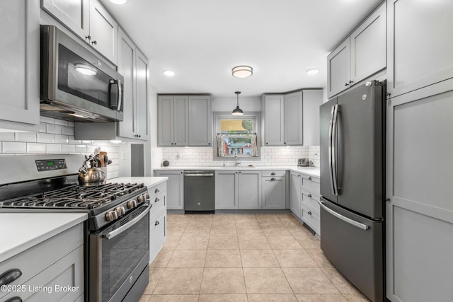kitchen with stainless steel appliances, light tile patterned flooring, tasteful backsplash, gray cabinets, and light countertops