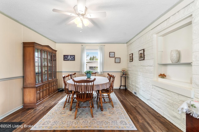 dining area with ornamental molding, a ceiling fan, dark wood-type flooring, and a textured ceiling