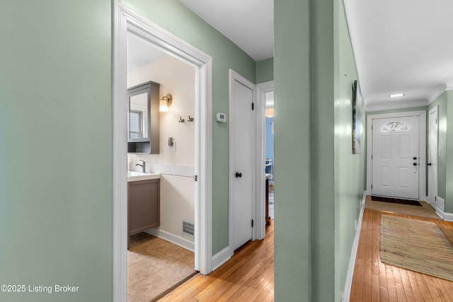 hall featuring baseboards, visible vents, and light wood-type flooring