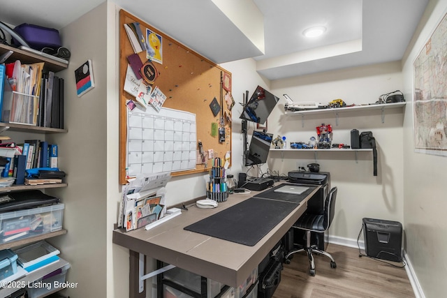 office area with baseboards, wood finished floors, and a workshop area
