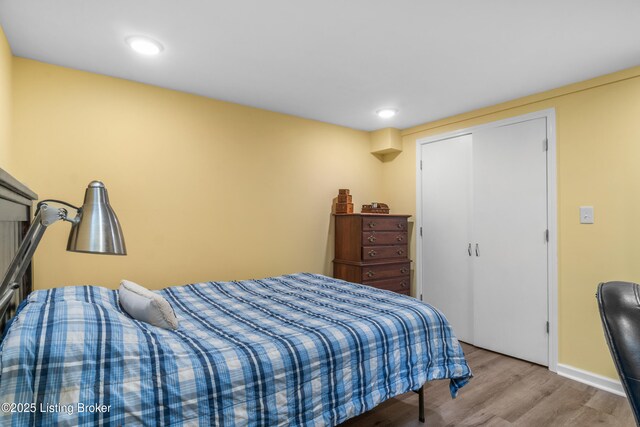 bedroom featuring baseboards, wood finished floors, recessed lighting, and a closet