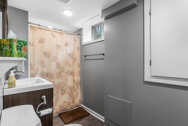 bathroom featuring a shower with curtain, a sink, toilet, baseboards, and wood finished floors