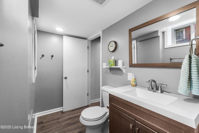 bathroom featuring wood finished floors, vanity, baseboards, toilet, and visible vents