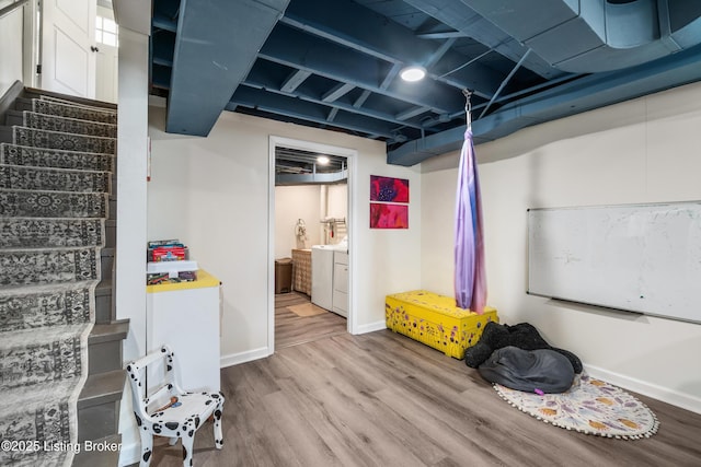 finished below grade area featuring washer and dryer, baseboards, wood finished floors, and stairs