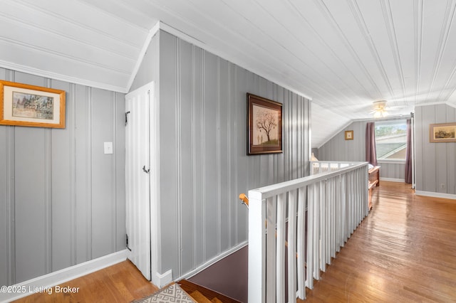 hall featuring light wood-type flooring, vaulted ceiling, baseboards, an upstairs landing, and crown molding