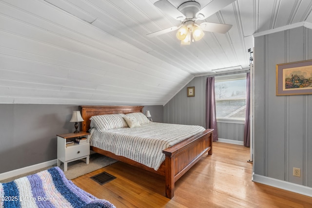 bedroom with a ceiling fan, light wood finished floors, baseboards, lofted ceiling, and visible vents
