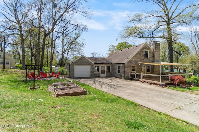 rear view of house with a chimney, aphalt driveway, a garden, an attached garage, and a lawn