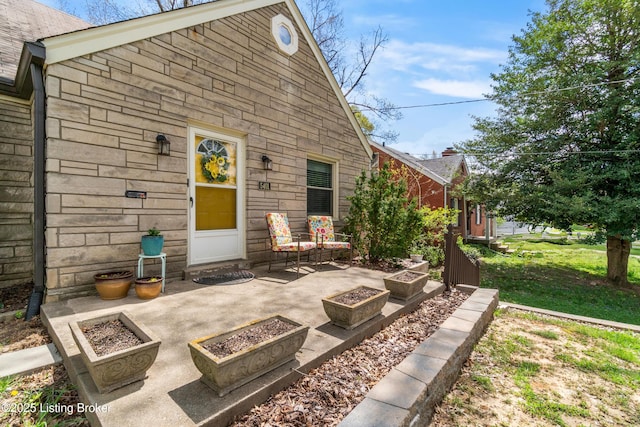 exterior space with stone siding, a patio, and an outdoor fire pit