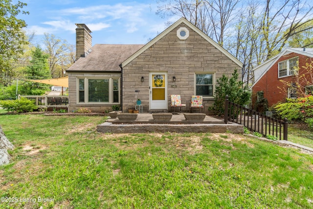 new england style home featuring a chimney, a front lawn, fence, and stone siding
