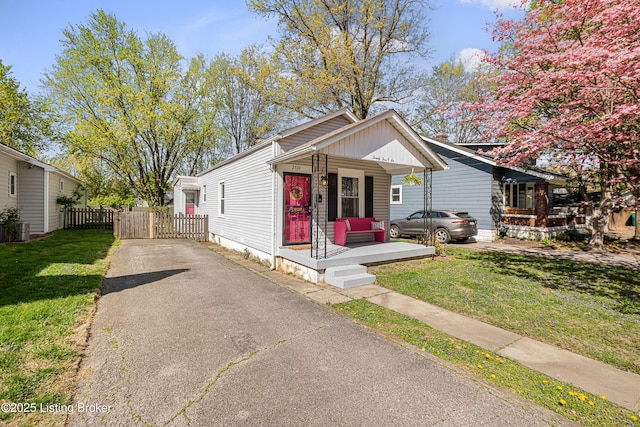 view of front of home with driveway, fence, a front yard, and covered porch