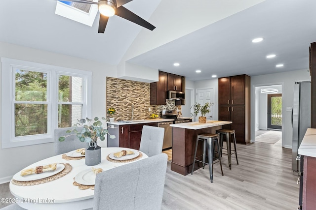 interior space with stainless steel appliances, light countertops, backsplash, a ceiling fan, and a kitchen island