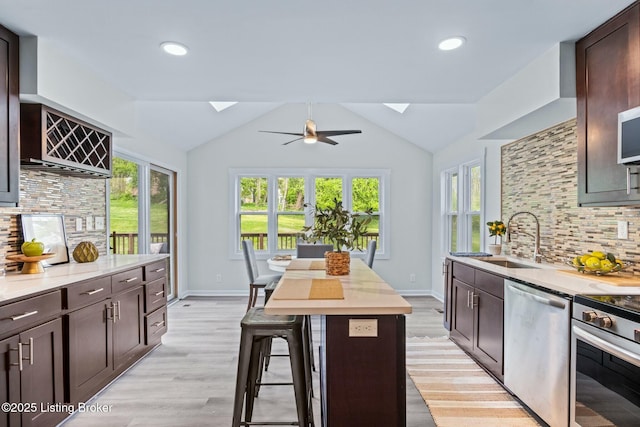 kitchen featuring dark brown cabinets, stainless steel appliances, light countertops, and a sink