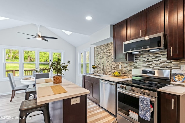 kitchen featuring light wood-style flooring, a sink, a ceiling fan, light countertops, and appliances with stainless steel finishes