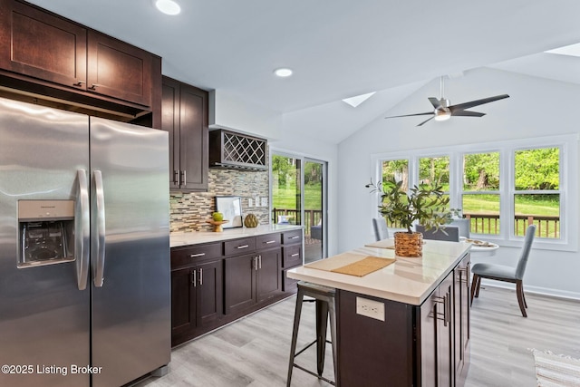 kitchen featuring light countertops, light wood-style floors, decorative backsplash, stainless steel fridge, and ceiling fan