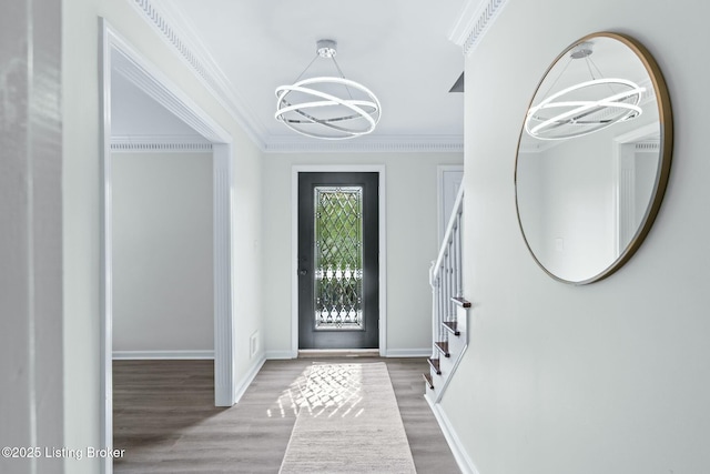 foyer entrance with baseboards, an inviting chandelier, wood finished floors, stairs, and crown molding