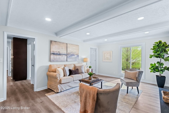 living area with a textured ceiling, wood finished floors, beam ceiling, and baseboards