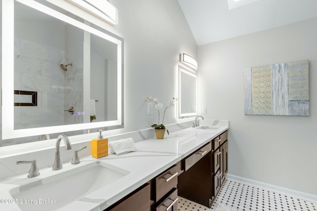 bathroom with baseboards, vaulted ceiling, a sink, and tiled shower