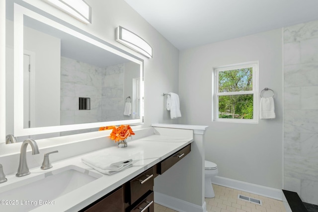 bathroom with tiled shower, toilet, baseboards, visible vents, and vanity