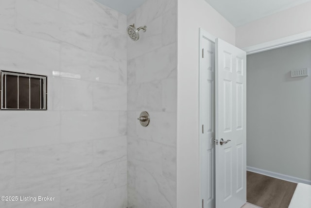 full bath featuring wood finished floors and a tile shower