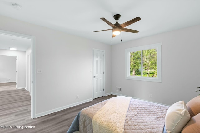 bedroom featuring ceiling fan, baseboards, wood finished floors, and visible vents